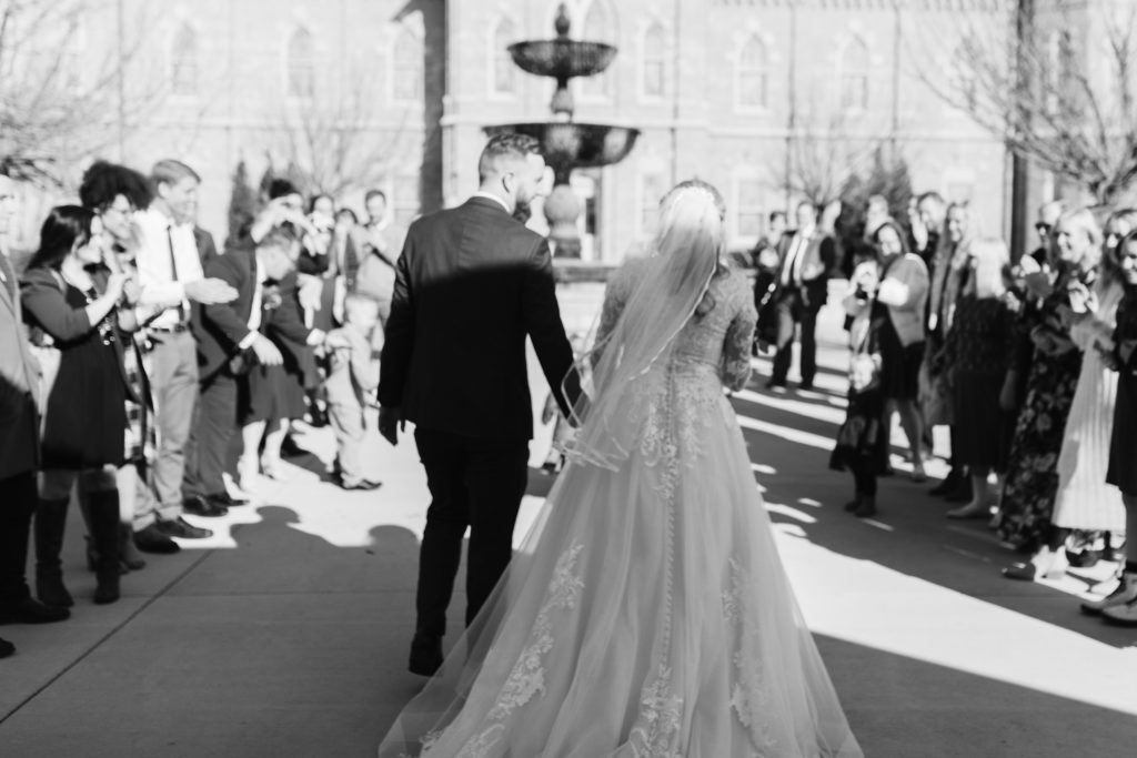Black and white image of Abigail and Justin greeting their family in front of the Provo City Center Temple.